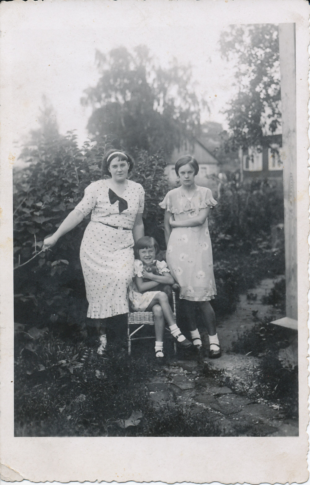 Iš kairės stovi motina J. Degutienė, pintoje kėdėje sėdi Janina su katinu, dešinėje – teta Zofija. Telšiai, apie 1935 m.