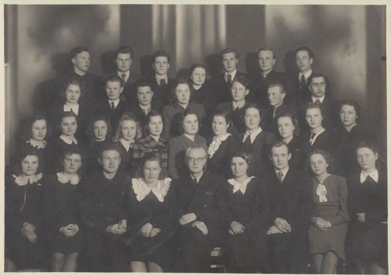 Profesorius V. Mykolaitis (sėdi centre) su Vilniaus universiteto lituanistais. Pirmoje eilėje antra iš dešinės sėdi Meilė Kudarauskaitė, trečioje eilėje ketvirta iš kairės – Janina Degutytė. 1953 04 06.  MLLM 55342