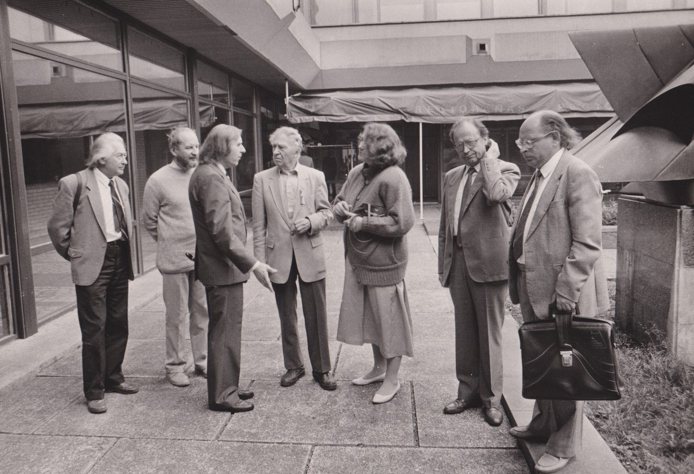 Iš kairės pirmas H. A. Čigriejus, antras K. Nastopka, trečias J. Juškaitis, ketvirtas B. Brazdžionis, penkta V. Jasukaitytė, šeštas M. Vainilaitis, septintas J. Strielkūnas. 1989 m. A. Žižiūno nuotrauka. MLLM 133977