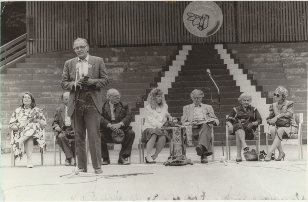 Poezijos pavasaris: V. Jasukaitytė, J. Strielkūnas, E. Matuzevičius, D. Lovett, B. ir A. Brazdžioniai, neatpažinta moteris. Prie mikrofono stovi aktorius L. Noreika. 1989 m. O. Pajedaitės nuotrauka. MLLM GEK 137763
