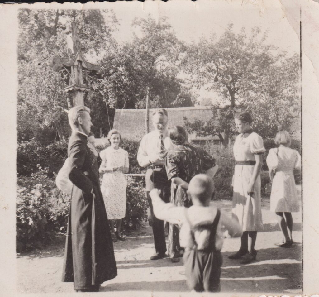 Jono Būgos šeima su į svečius atvykusiu istoriku, mokslinės archeologijos pradininku Jonu Puzinu (1905–1978) (stovi centre). 1943 m. Pažiegėje po Joninių. Autorius nežinomas. MLLM 31940