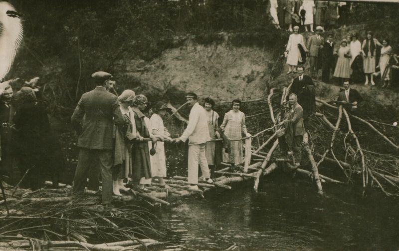 Teologijos – filosofijos fakulteto gegužinė. J. Eretas (baltu kostiumu ant tiltelio), V. Mykolaitis-Putinas (juodu kostiumu kitoje tilto pusėje). Kitame krante S. Nėris ir O. Jakaitytė. Pajiesys, 1926 06 02. MLLM 22592