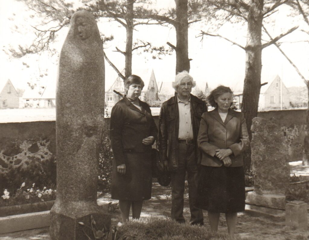 Pošūpių kapinėse prie paminklo tėvams. Rašytojui iš šonų stovi seserys Adolfa Avižiūtė (kairėje) ir Stasė Valančiunienė. 1991 m. rugsėjis. MLLM 76042