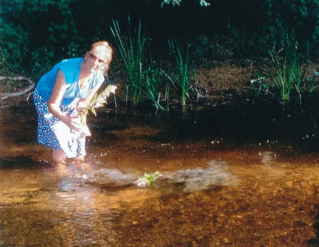 Aldona Kvedaraitė-Stark barsto vyro pelenus Kražantės upėje