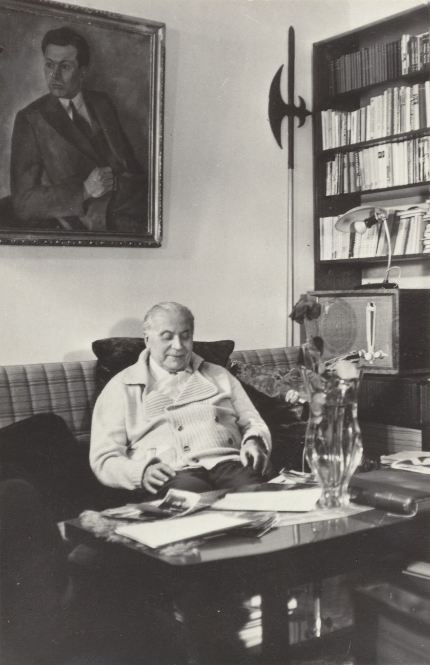 J. Grušas savo darbo kabinete. Kaunas, 1976 m. R. Rakausko nuotrauka. Kambario kampe atremta alebarda.