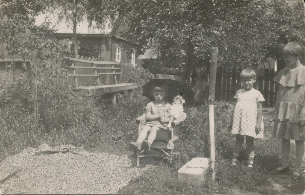 Janina Degutytė sėdi po skėčiu lėle, iš dešinės pirma – teta Zofija Bedarfaitė. Kaunas, Šančiai Kranto 6-oji gatvelė, 1931 m.