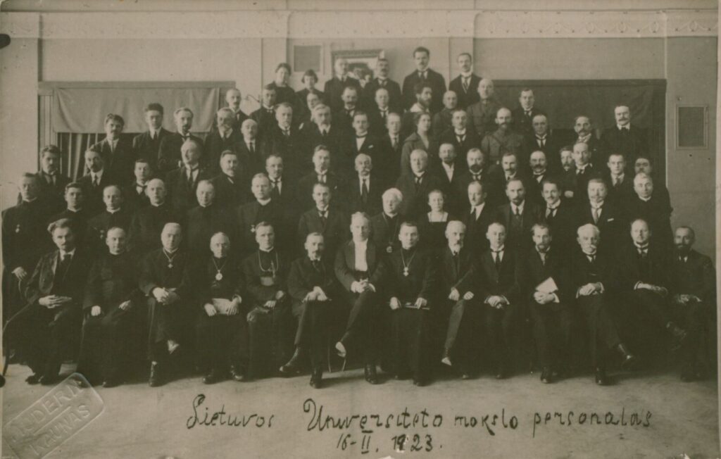 Lietuvos universiteto dėstytojai. I-oje eilėje trečias iš kairės sėdi poetas, kunigas Maironis, jo dešinėje – kunigas, kritikas Adomas Jakštas-Dambrauskas; II eilėje aštuntas iš kairės sėdi kunigas, rašytojas, Juozas Tumas-Vaižgantas. Kaunas. MLLM 95611