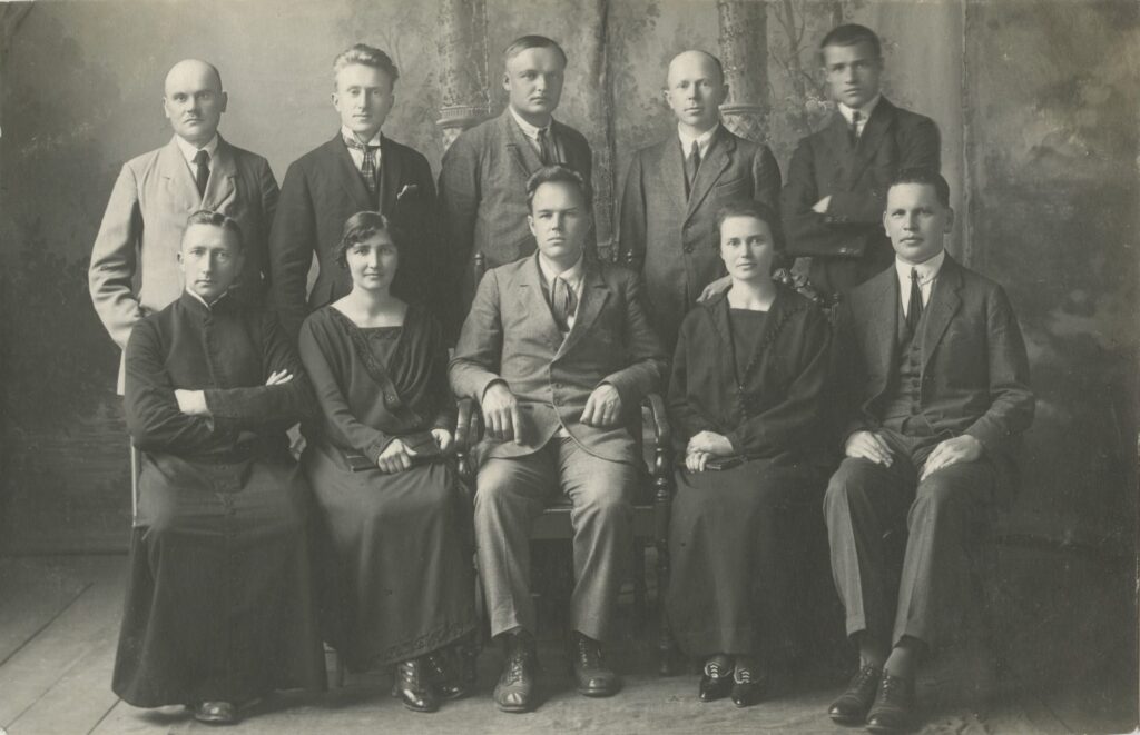 I eilėje iš kairės: kapelionas kun. Povilas Šidlauskas, Ona Mataitytė-Geniušienė, dir. Antanas Giedraitis ir kiti. Jurbarkas. Apie 1923 m. Panevėžio apskrities Gabrielės Petkevičaitės-Bitės viešoji biblioteka, Povilo Šidlausko fondas F177_122